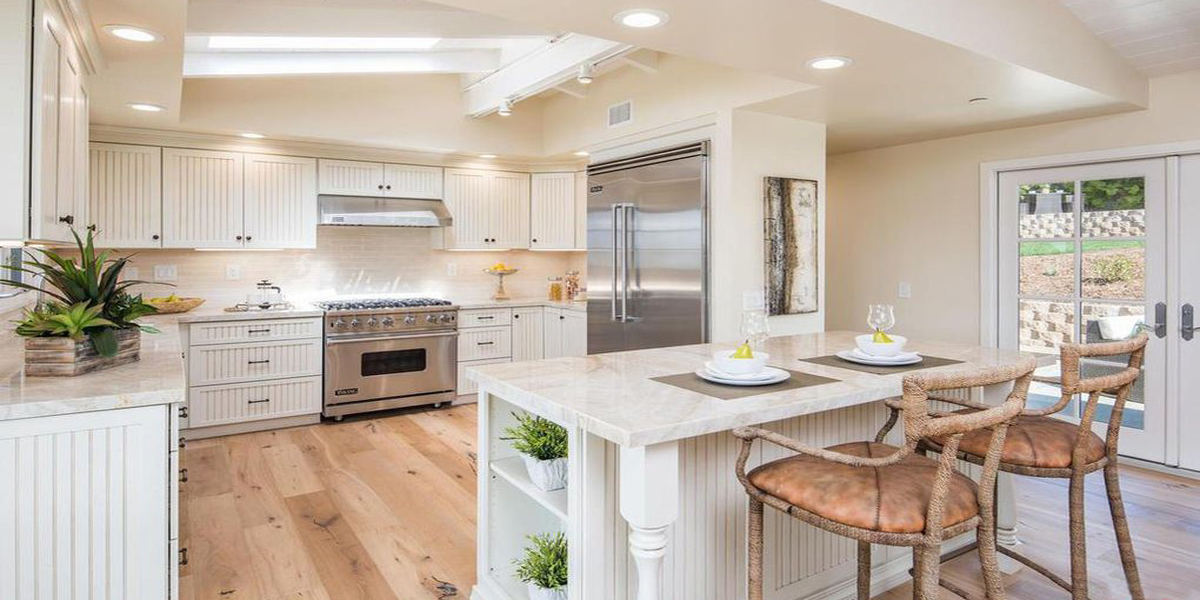 kitchen remodel featuring European oak wood floors, white painted cabinets and natural stone countertops